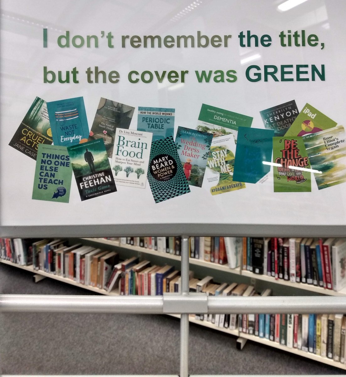 Sign on top of free-standing book trolley in public library that says "I don't remember the title but the cover was GREEN"