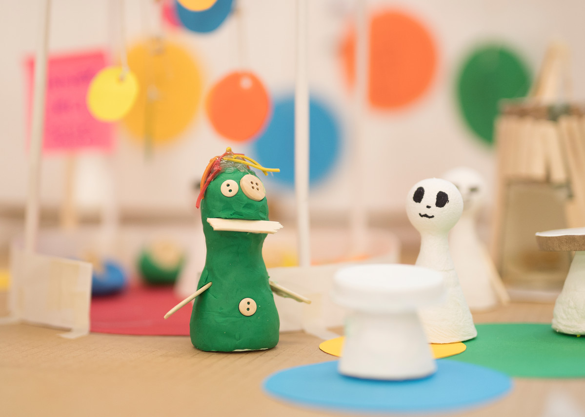 Close up image of part of a prototype, featuring a green figure made from plastacine with button eyes and a white figure which resembles a ghost.