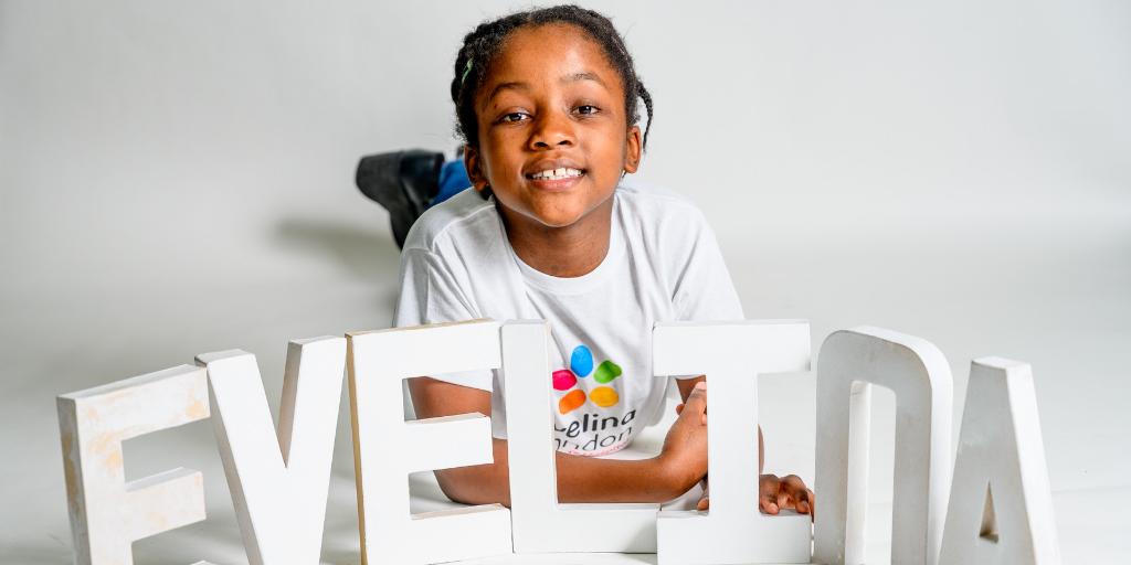 A girl smiling with a large sign that says Evelina
