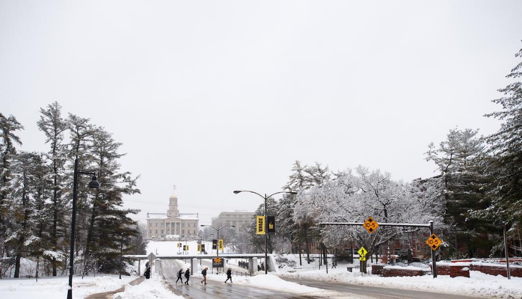 Students cross Iowa Avenue with the Old Capitol in the background.