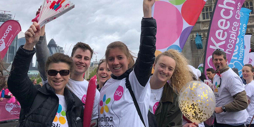 A group of people wearing Evelina London t-shirts cheering at a fundraising sports event.