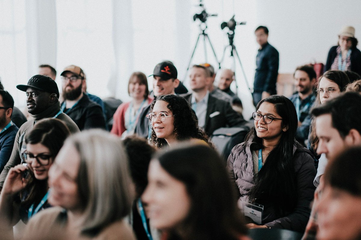 Netlify team members listen to presentations with cameras in the background