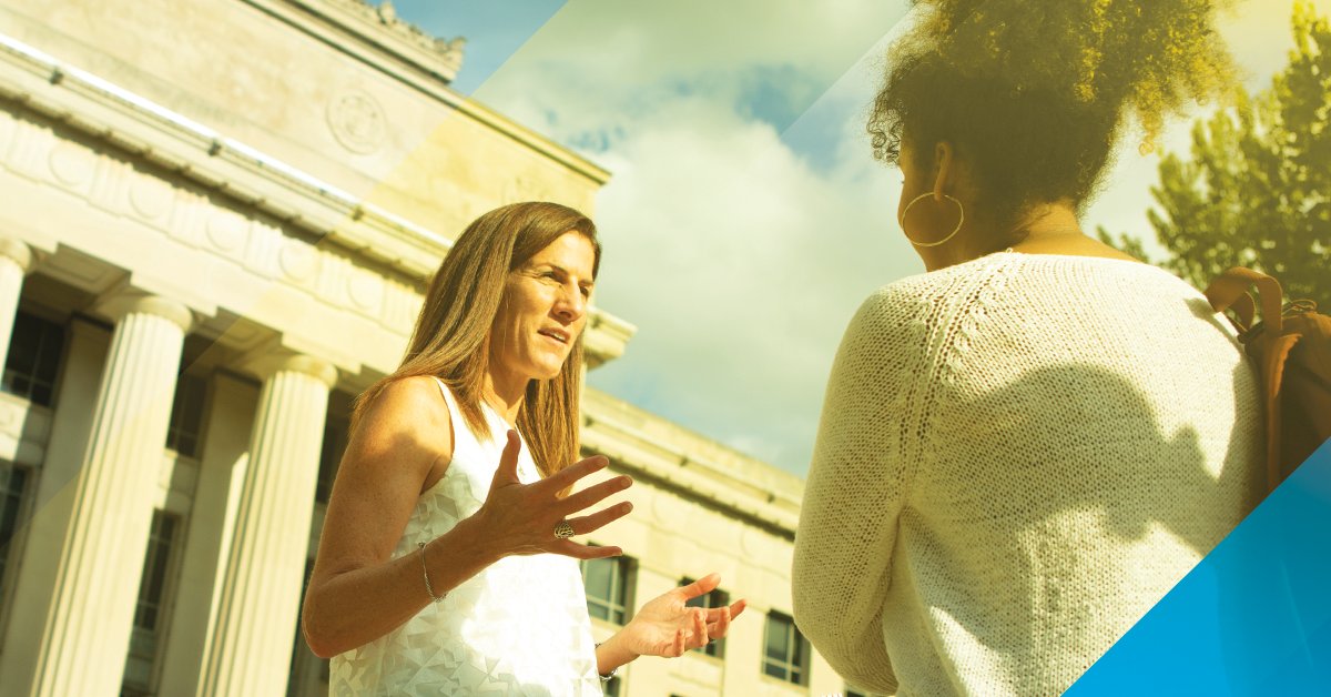 A photo of Dean Anne Curzan speaking with a student in front of Angell Hall. 