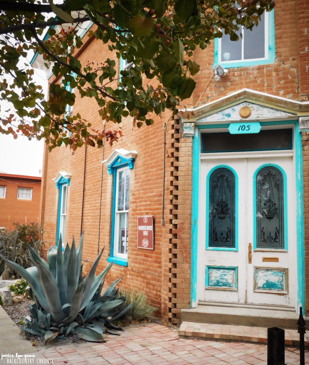 Door to the Warren House, a brick building with white door, turquoise trim, and large agave outside.