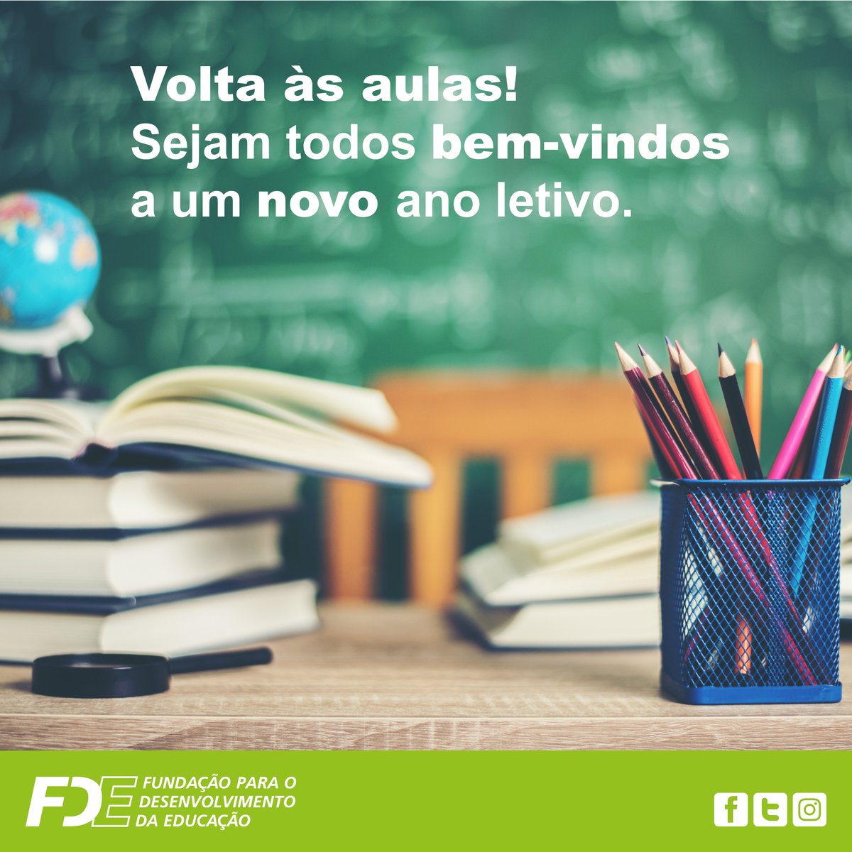 Ilustração de fundo de uma lousa desfocada, com a chamada na cor branca, centralizada no topo com a MSG: Volta às aulas! Sejam todos bem-vindos a um novo ano letivo. 
Sobre a mesa, alguns livros, um globo e uma lupa. E, do lado direito, um porta-lápis com alguns lápis coloridos.No rodapé, o logotipo da FDE e os ícones das redes sociais (Facebook, Twitter e Instagram).