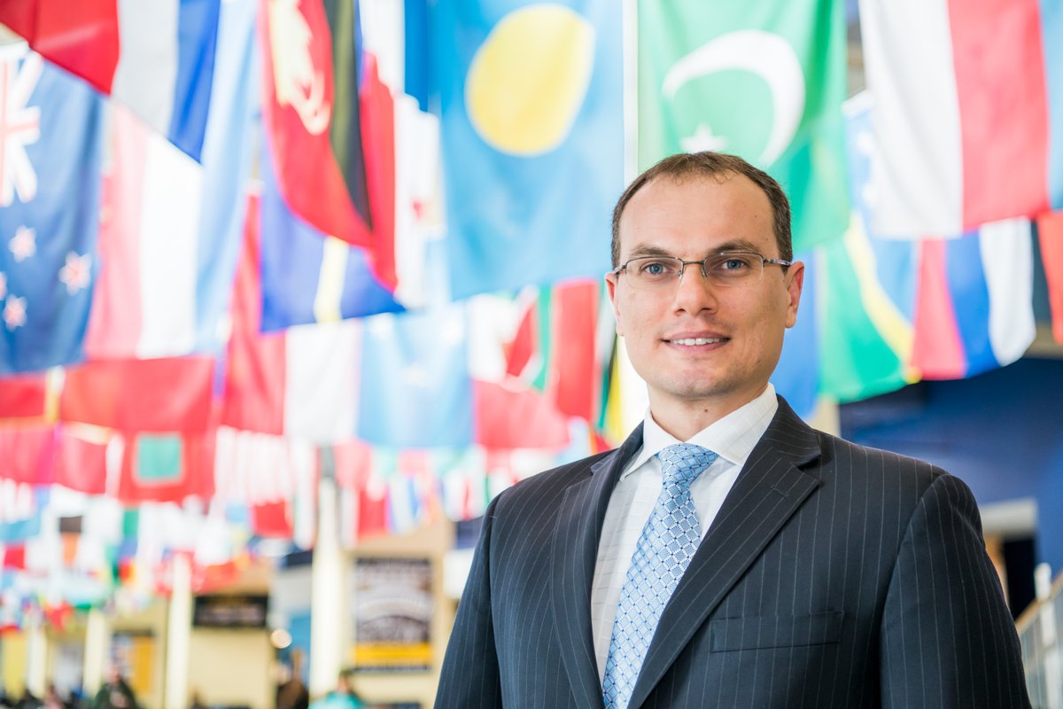 Man standing in front of several flags
