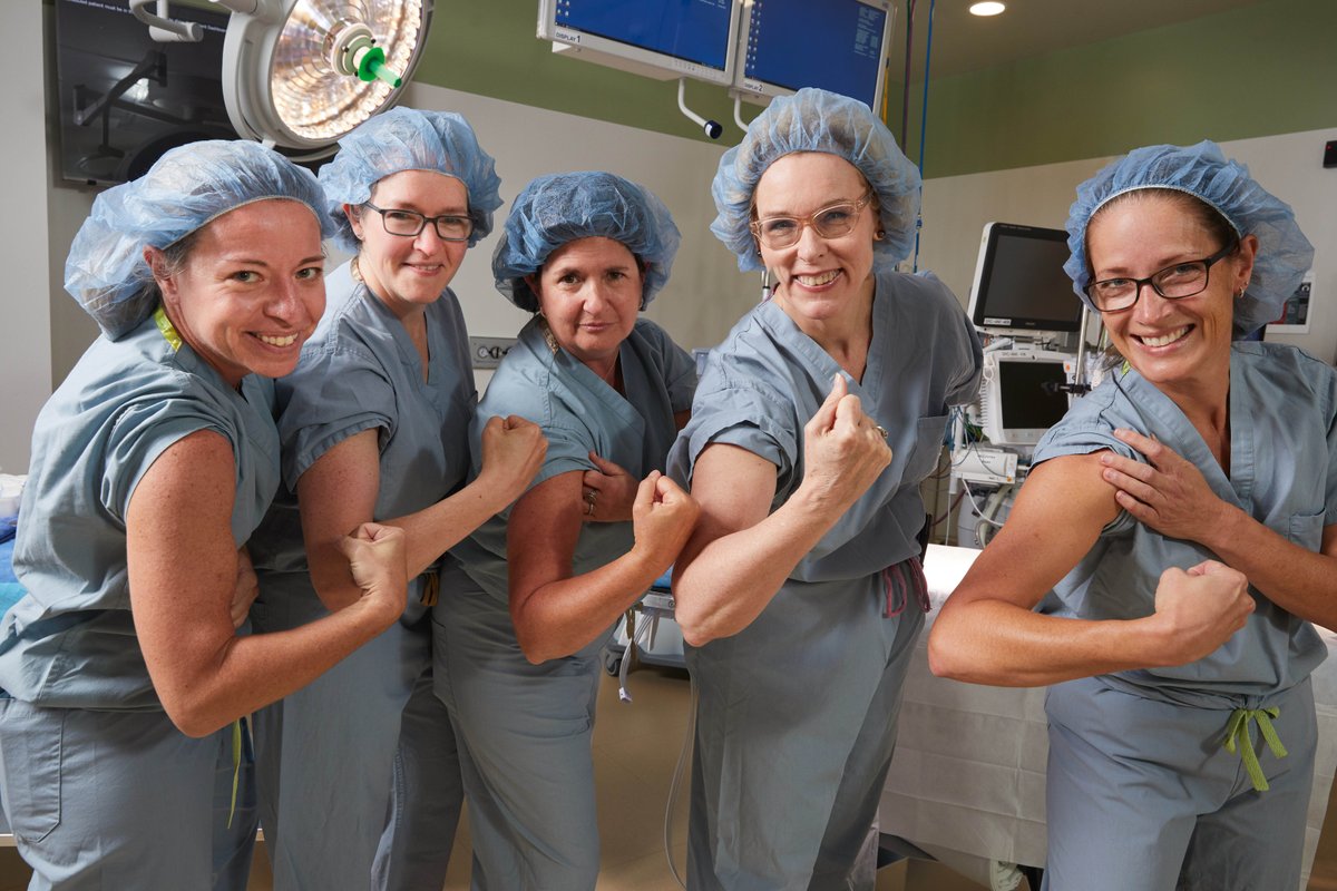 Women surgeons flexing their arms in an operating room.