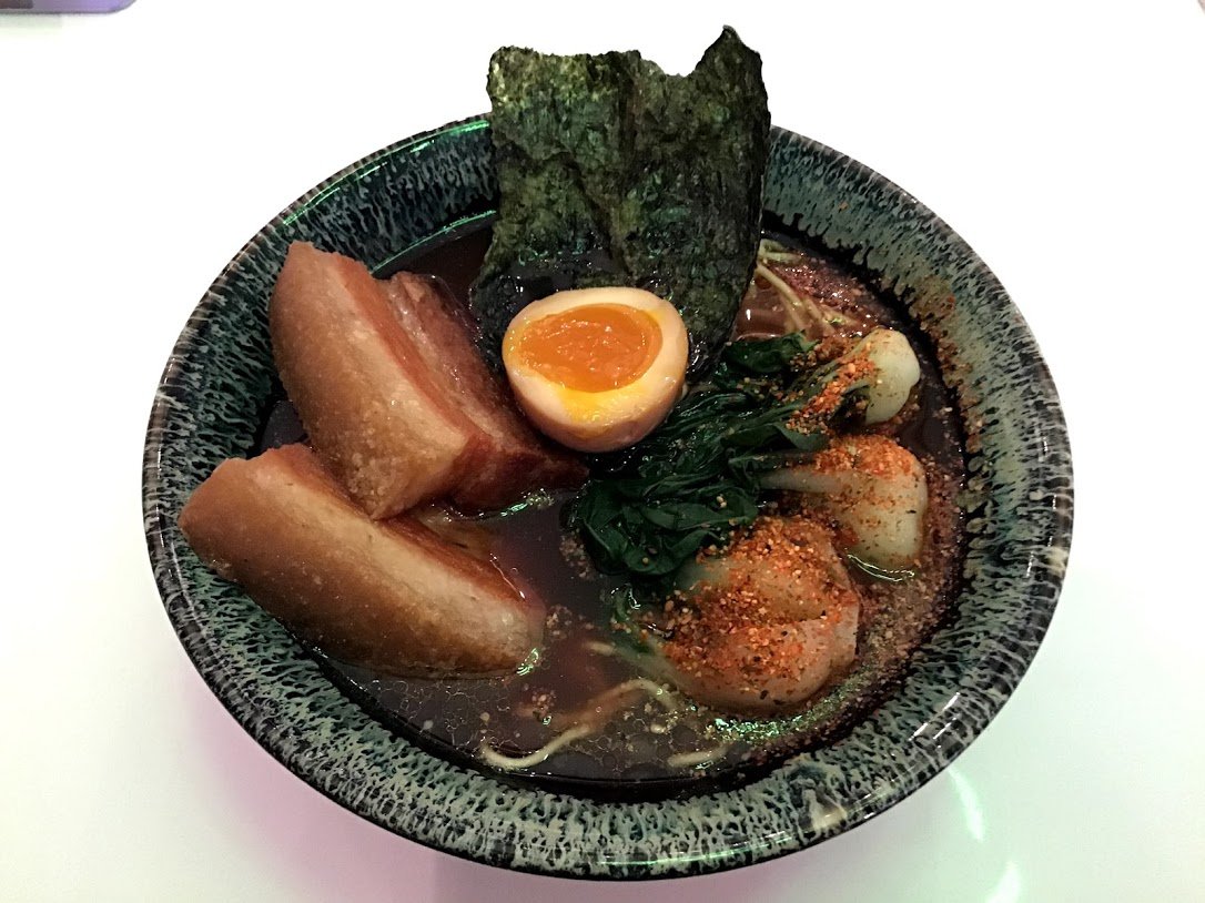 a bowl of ramen with fried pork belly, bok choy, and egg