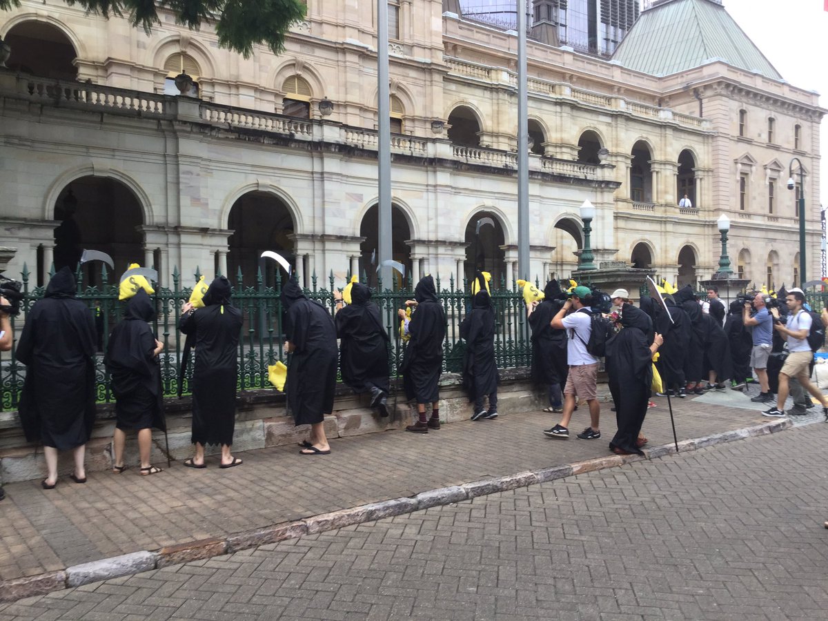 Grim reapers hanging bags of dirty coal money on Parliament House fence.