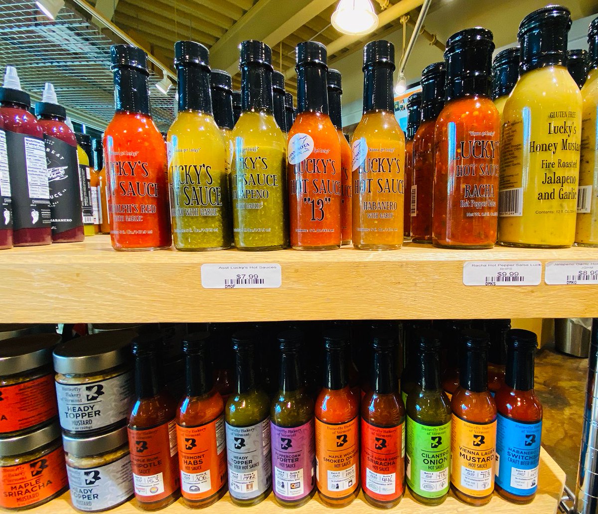 Two shelves hold lots of hot sauce bottles in many colors. The labels are a rainbow of hues, too.
