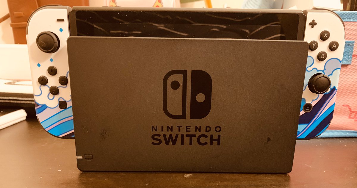 a nintendo switch console inside of its "dock" you can see the controllers poking out of the side.