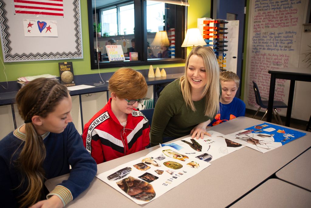 Teacher with three students at a table in a classroom.