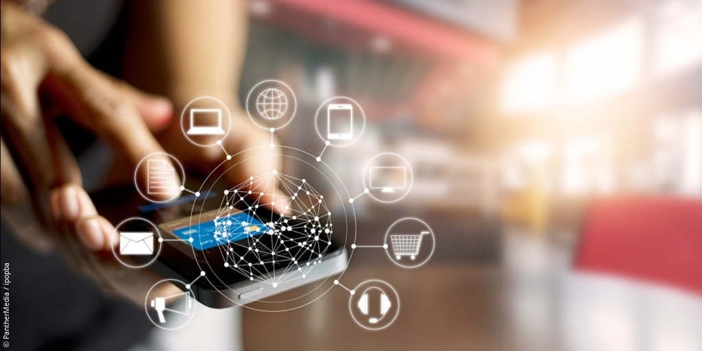 Photo: Man operates smartphone, several graphics swarm around it; Copyright: PantherMedia / ipopba