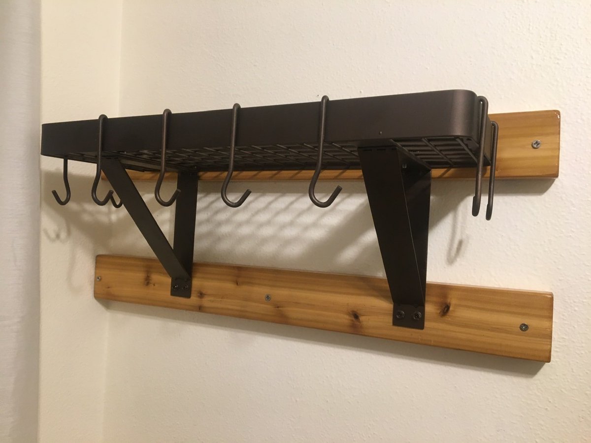 Cast iron pot rack mounted to two by fours on a white wall