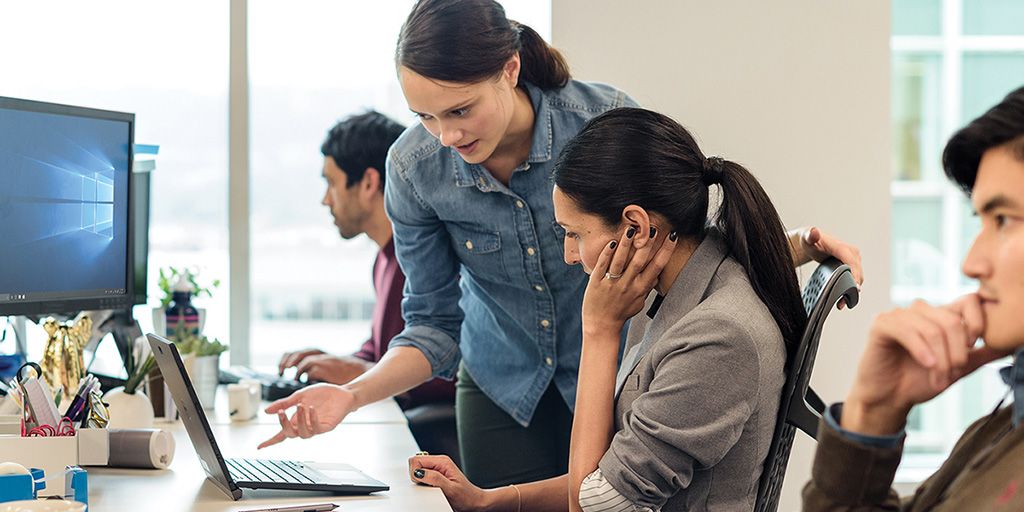 Two colleagues discussing their work with a Windows 10 desktop visible. 