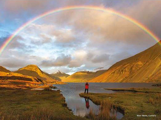 Man looking at rainbow over mountains and lakes