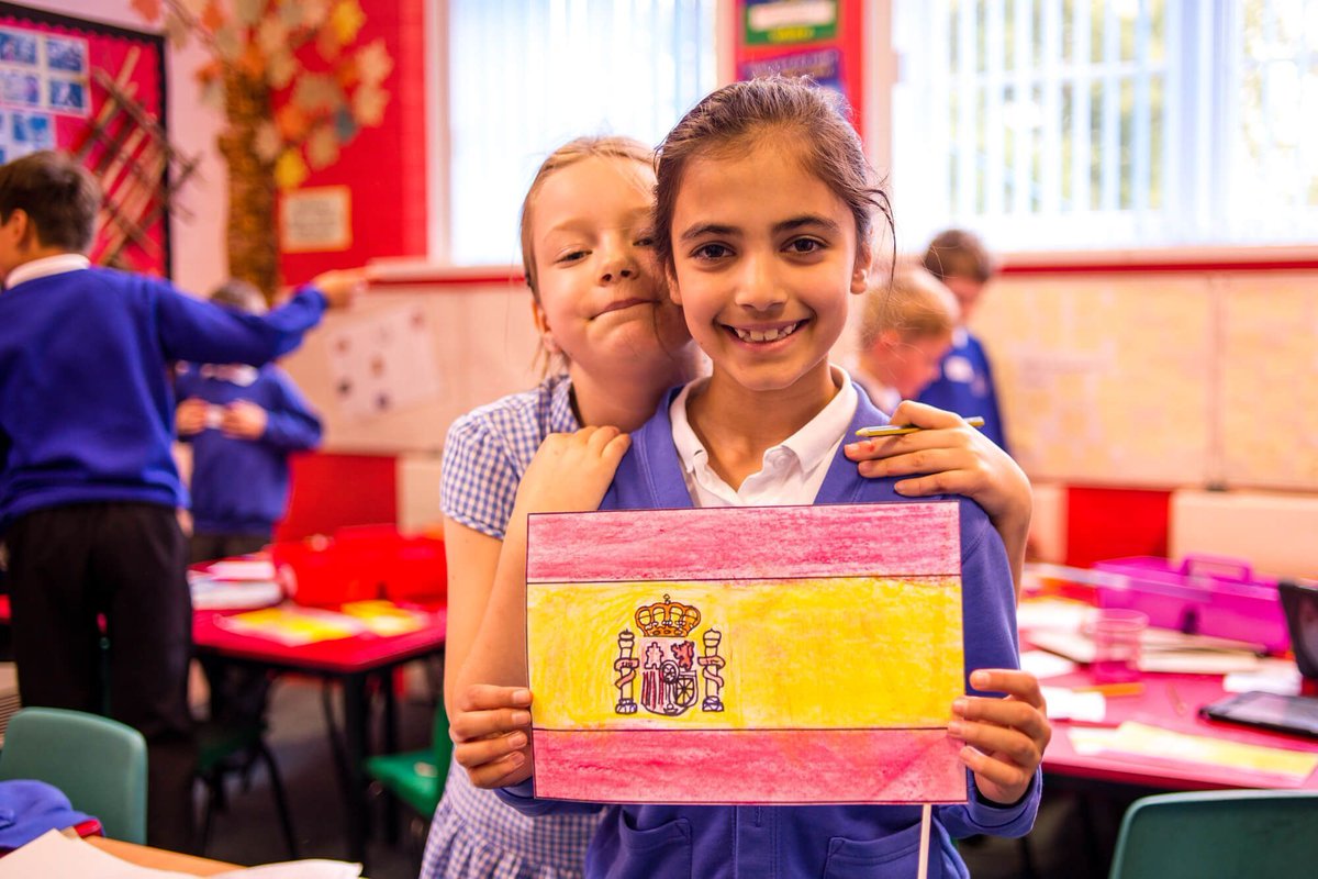 Two children smiling whilst holding the Spanish flag.
