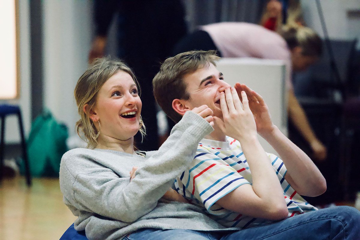 Two actors laughing sitting on a beanbag