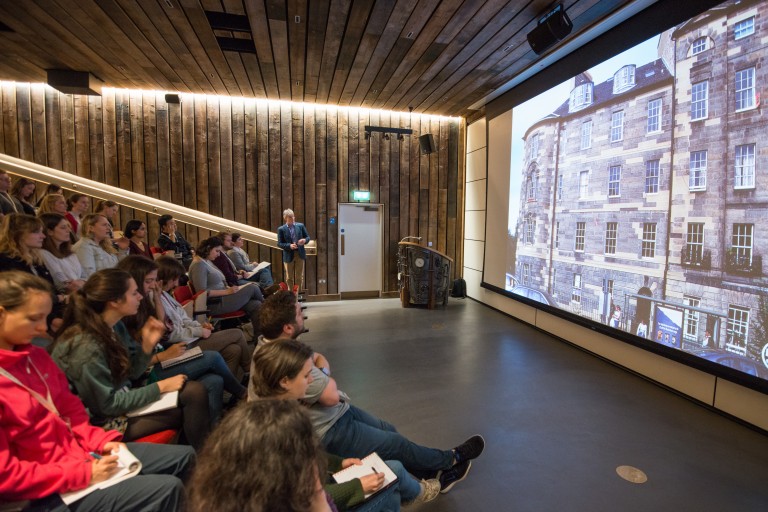 People inside the Engine Shed auditorium looking at a photo of a block of traditional tenements