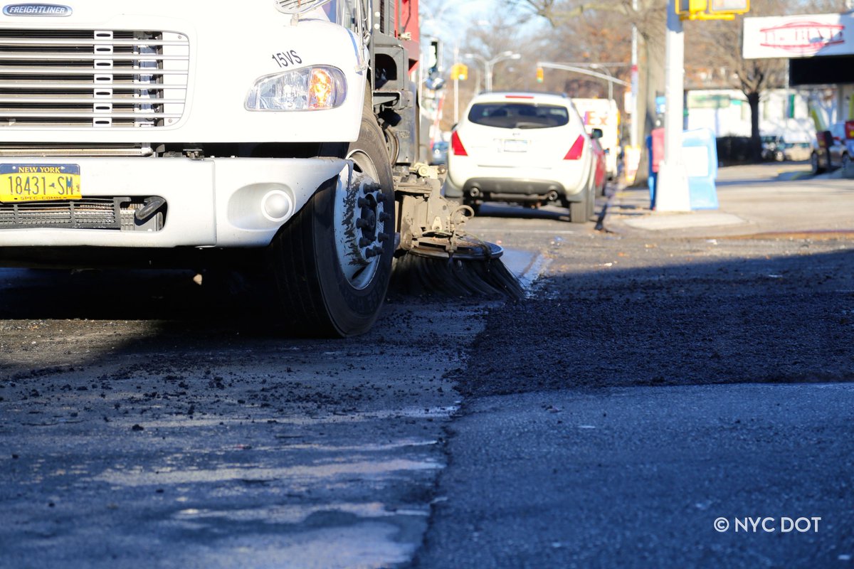 A street sweeper seen level with the camera on a newly paved street.