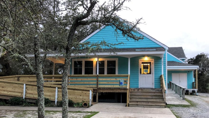A bright blue building with a long wooden wheelchair ramp and wood steps