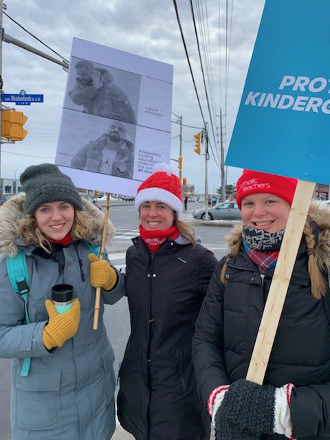 Three teachers holding signs at the strike signs.