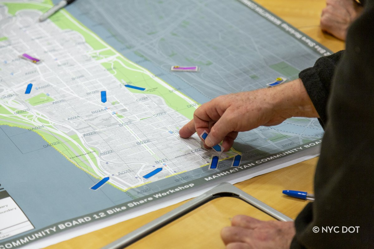 A person standing over a table placing stickers onto a map 
