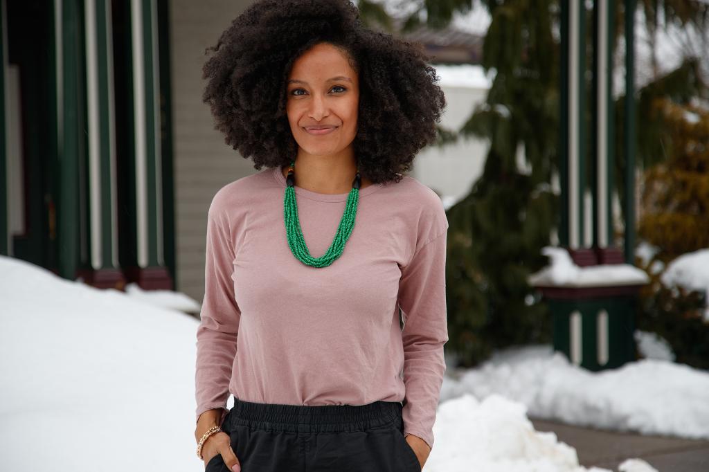 Kiley Reid looks at the camera smiling, hands in pocket.