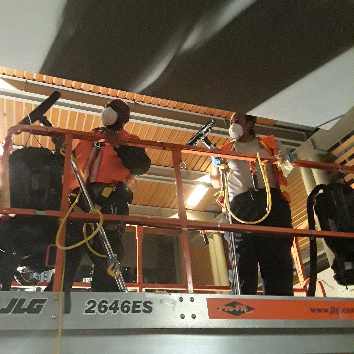 two workers on a high reach with vacuum cleaners