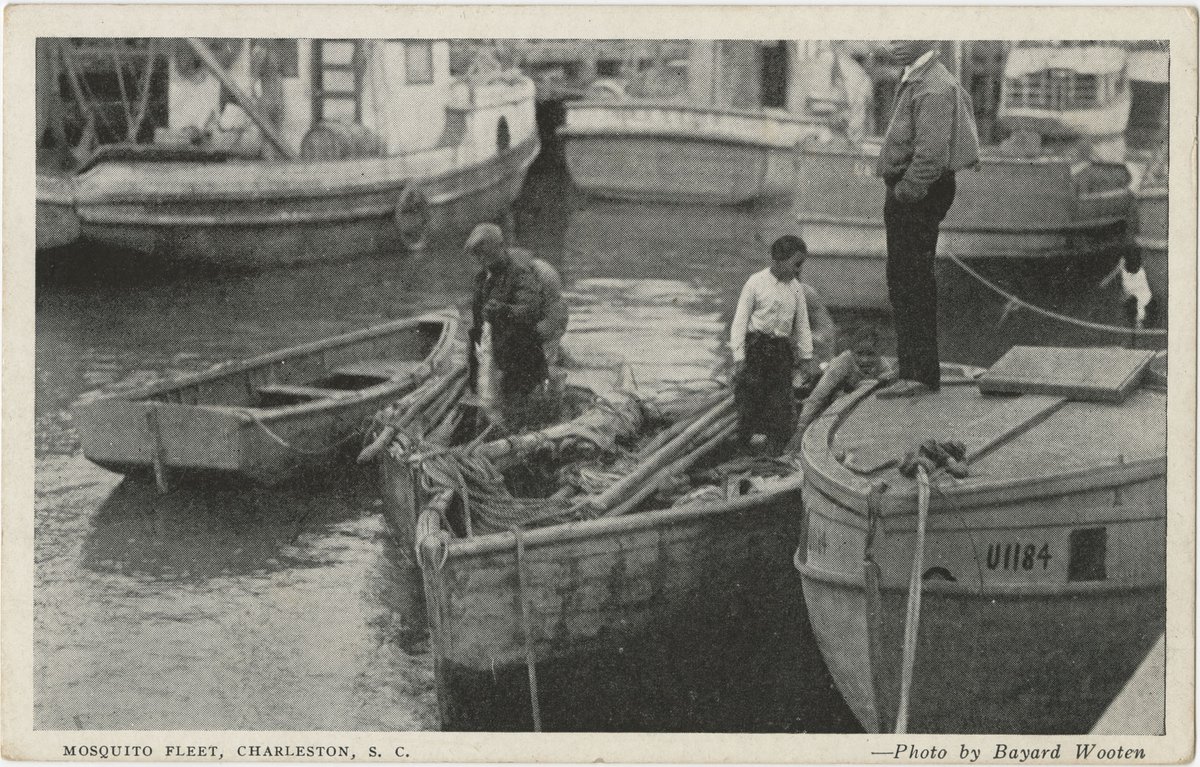 Two African American men stand in a small boat while one man stands next to them on a dock. 