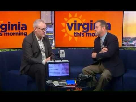 Richard sitting on a couch next to the news anchor while demonstrating the Acrobat MINI in the news segment.