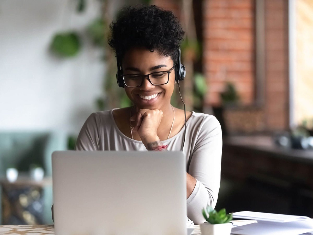 A student studying at a laptop, whilst wearing headphones. 