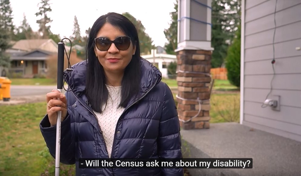 A woman with long dark hair wearing dark glasses, alongside a white cane, faces the camera. A visible caption reads: "Will the Census ask me about my disability?" 