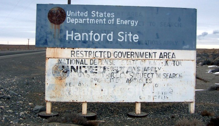 An old faded sign, blue on top white on bottom reading "United States Department of Energy Hanford Site." 
