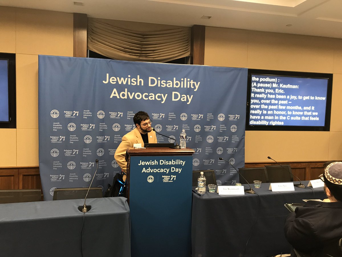 Aaron Kaufman stands at a podium and addresses the JDAD audience