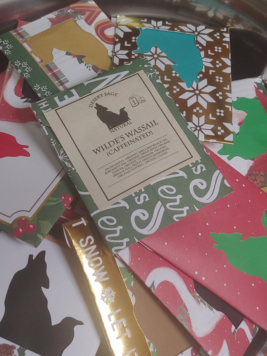 A pile of decorative single teabag packets, fanned in spirals in a bowl.  The top one is labeled "Wilde's Wassail."