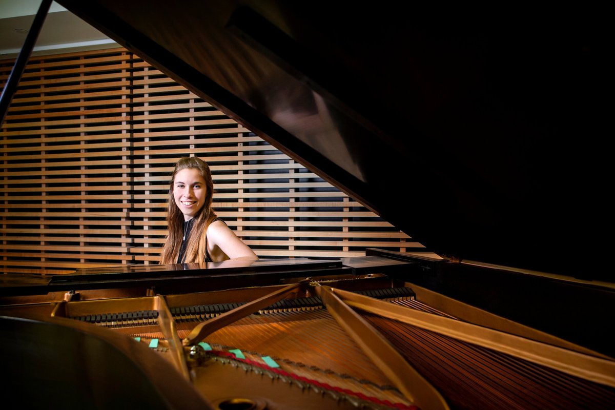 Katie Vukovics poses for the photo while sitting at a piano.