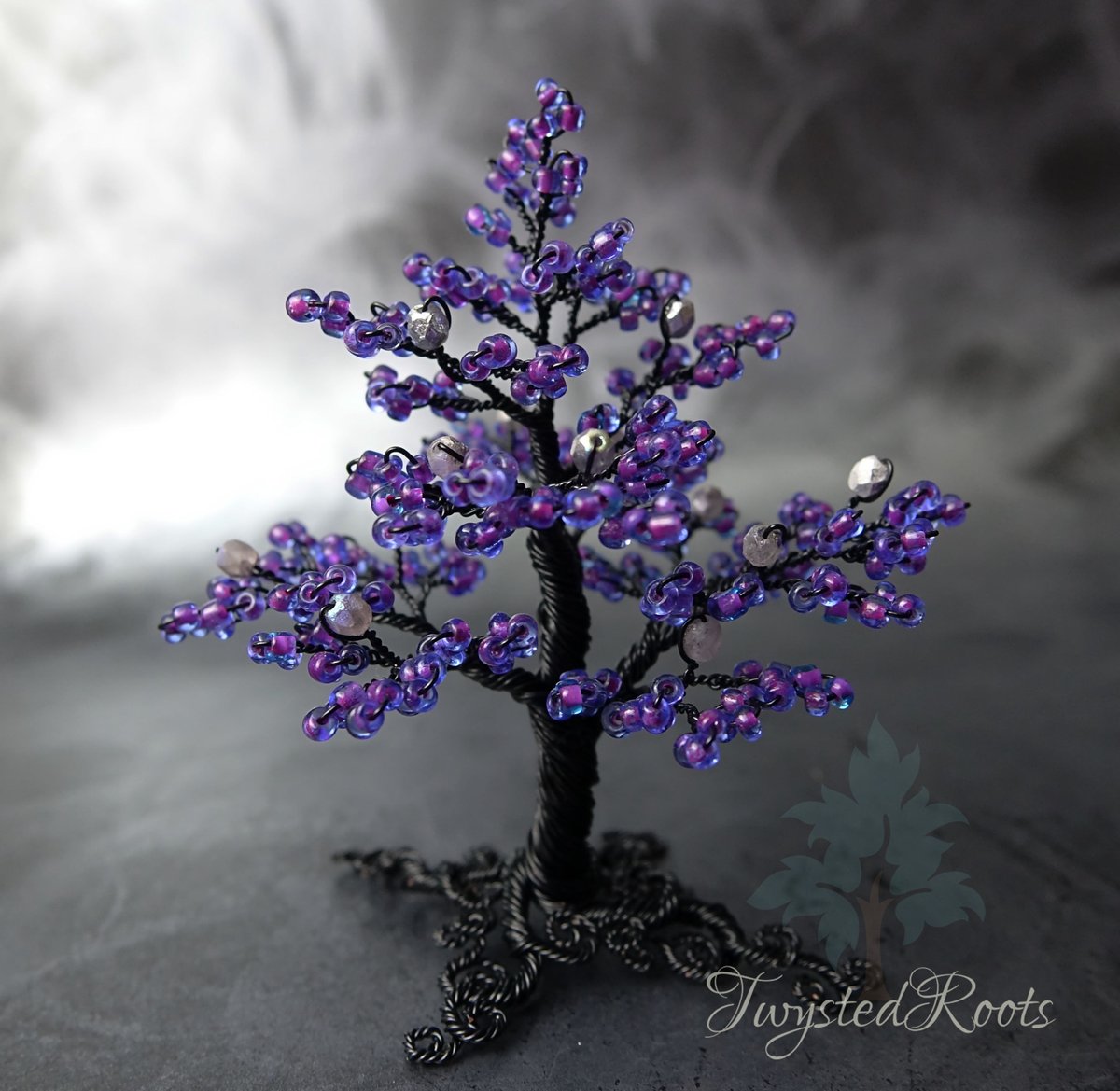 Purple black and silver bead and wire tree sculpture. Background is a misty grey effect. Twysted Roots logo is in the bottom right corner. 