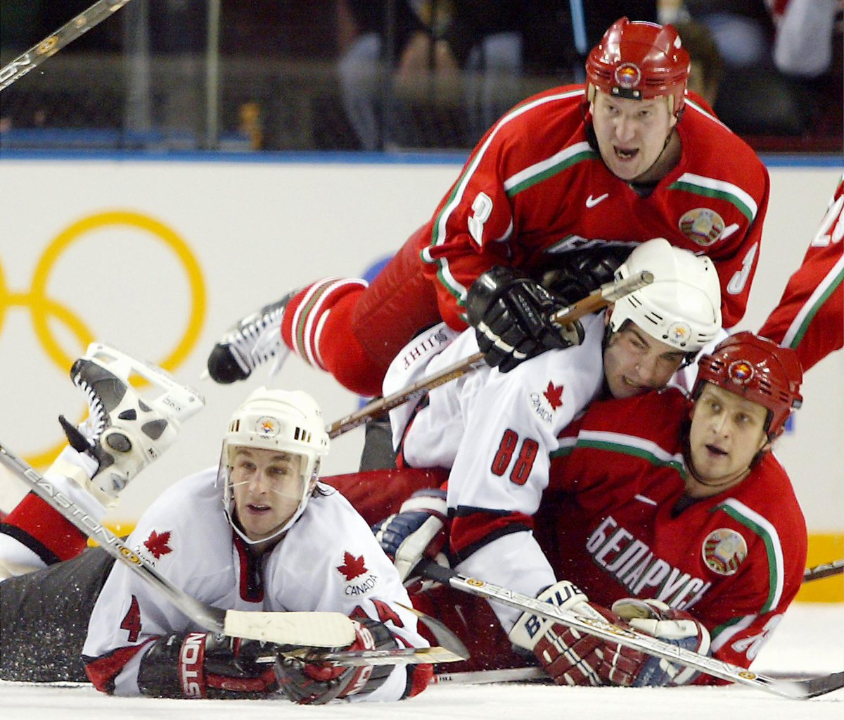 Ryan laying on the ice with Eric Lindros who is sandwiched in between two Belarus players.