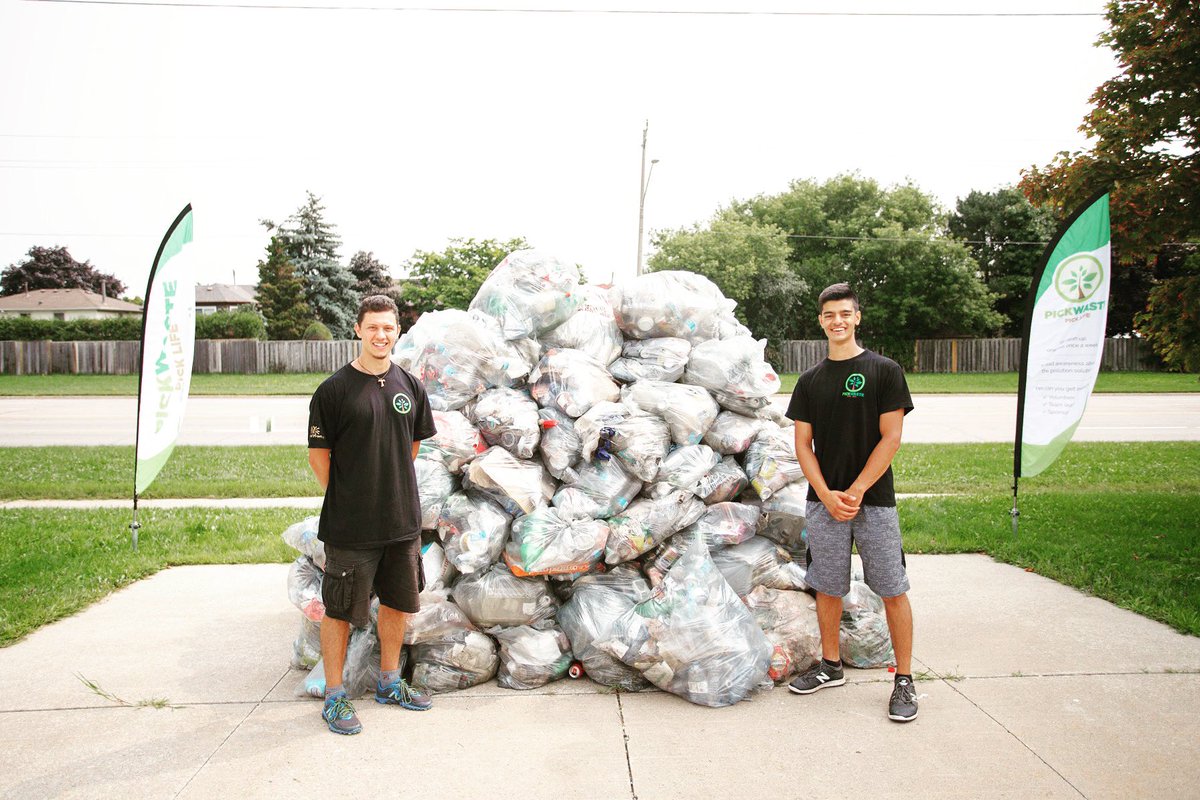 Men standing in front of a huge pile of full garbage bags from a clean-up