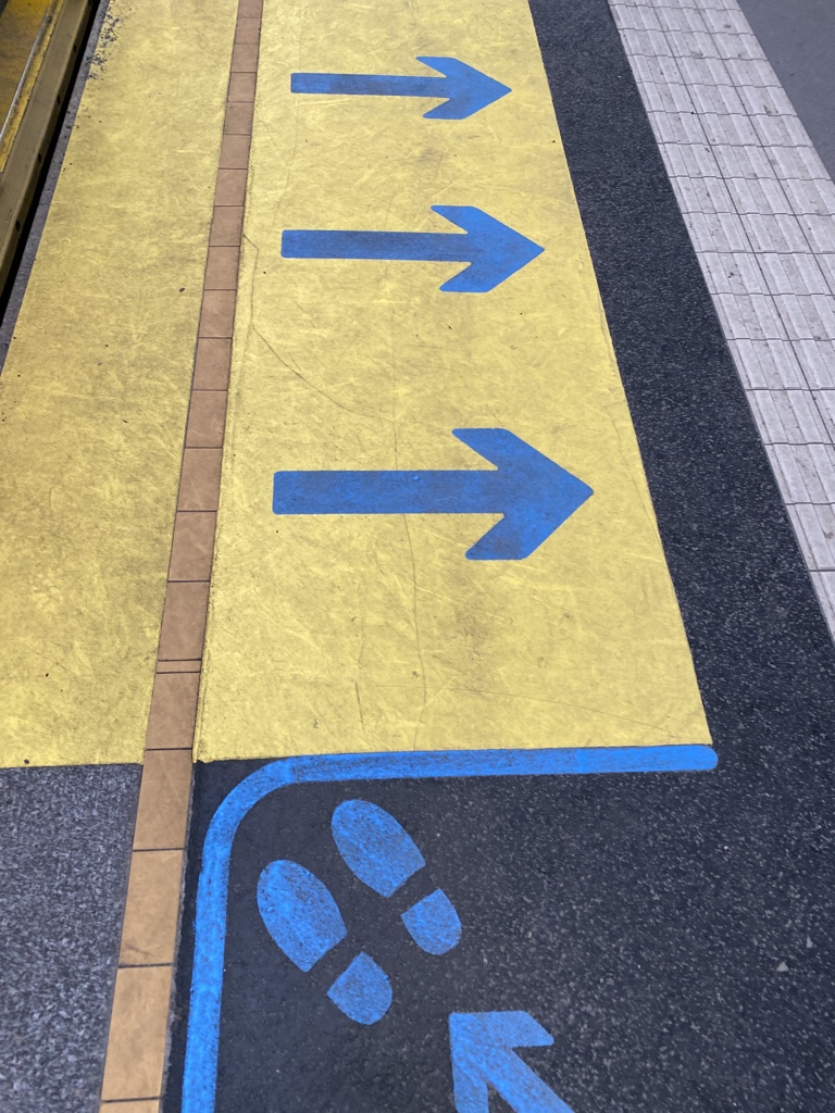 Yellow marking with blue arrows to indicate door positioning and people exiting the train. Blue footprints indicating where people who want to board should stand. 