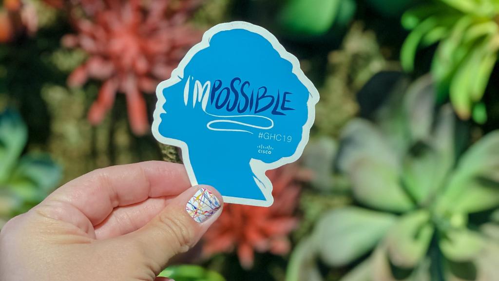 A hand holding a sticker the says I'Mpossible