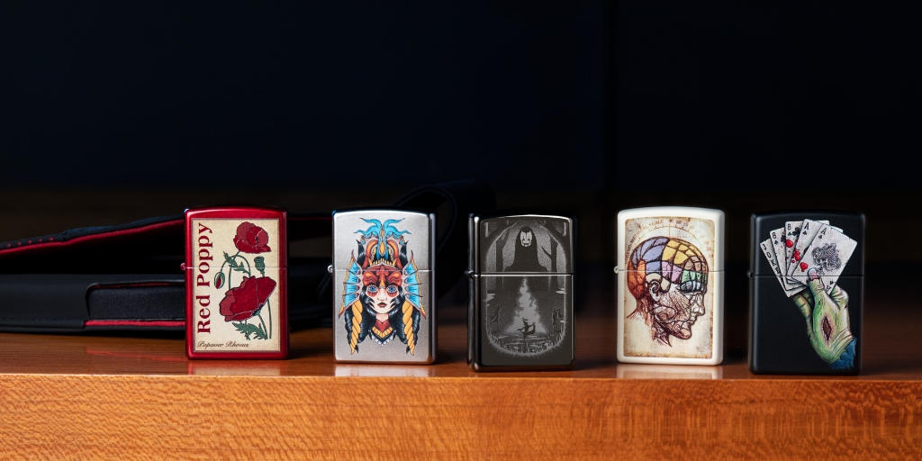 Five Zippo lighters lined up, facing forward, on an edge of a table. 
