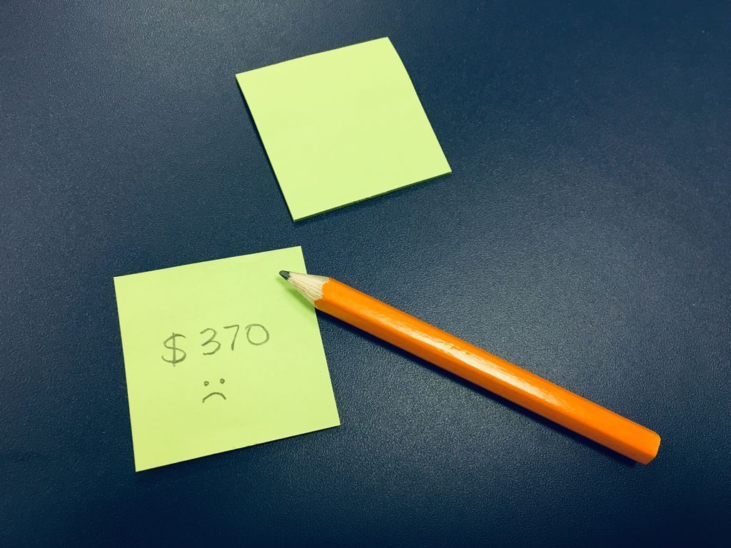 Une note autocollante qui dit 370$ avec une face triste. Il y a un petit crayon juste à coté.