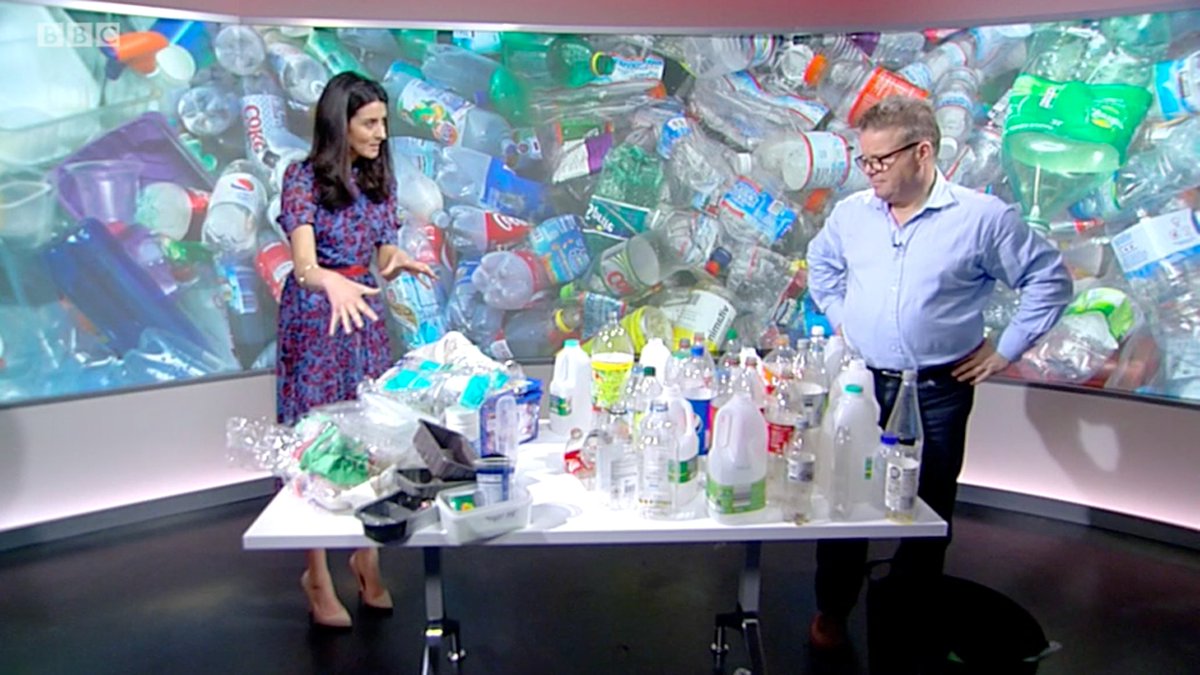 Professor Tony Ryan stands behind a table full of plastic, some recyclable and some not.