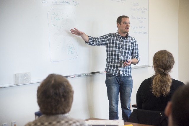 Photograph of a UC Davis graduate student presenting in front of a whiteboard. 