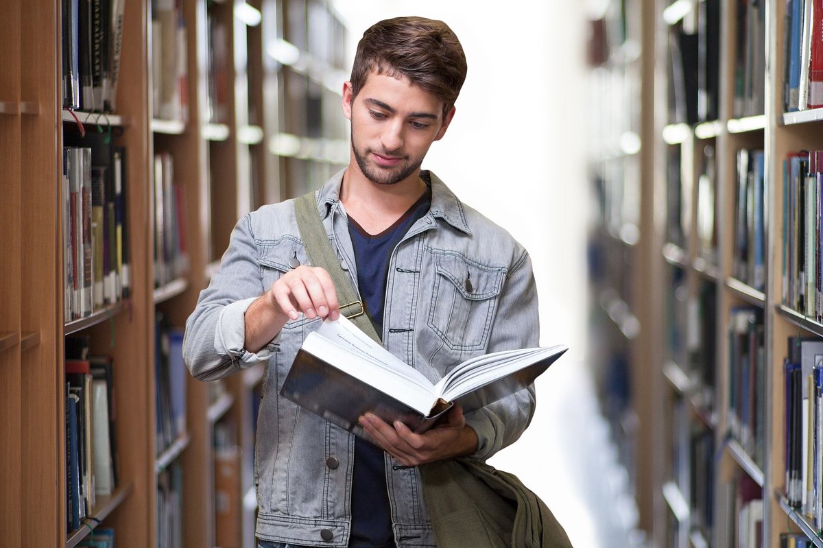 Male student in library reading book