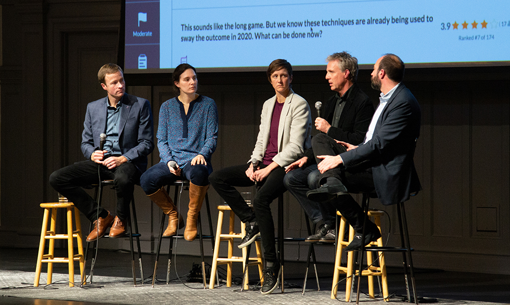 Chris Coward speaks, seated with four other panelists