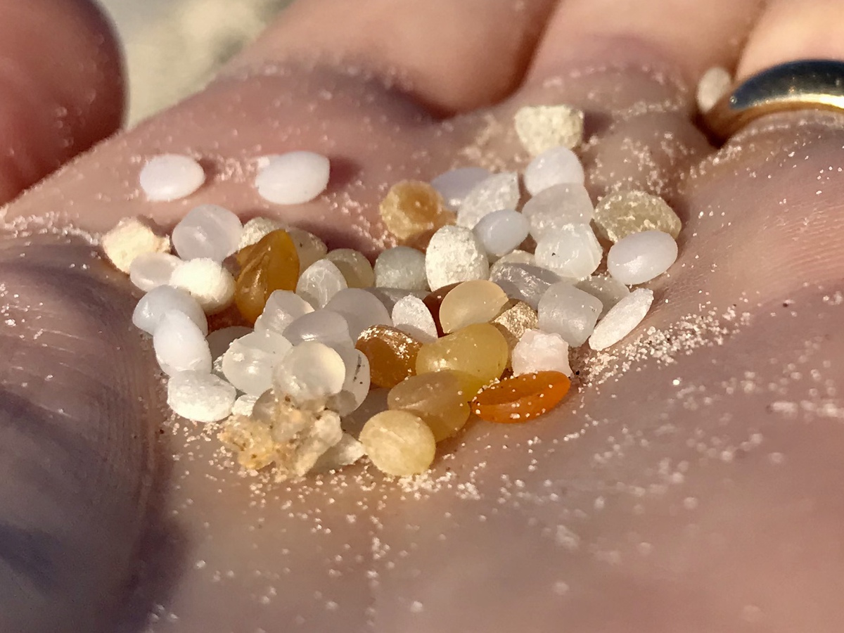 A hand holding nurdles or small microplastic pellets.