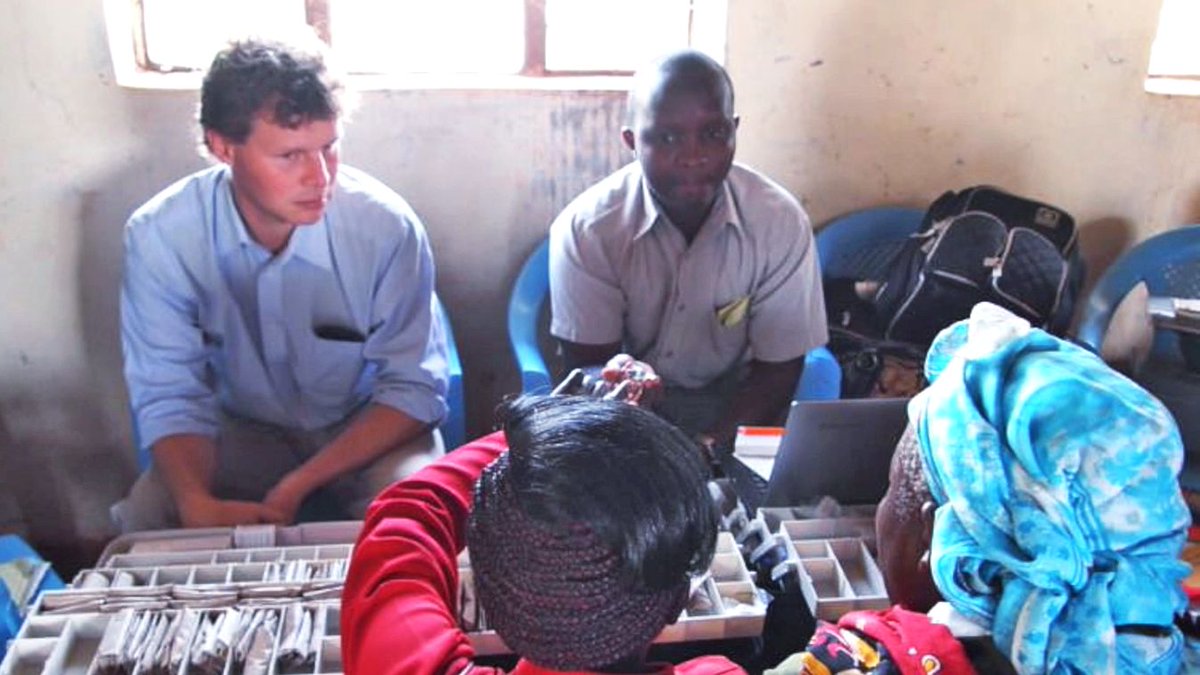Adrian and a colleague conduct a home health visit with a family in Kenya